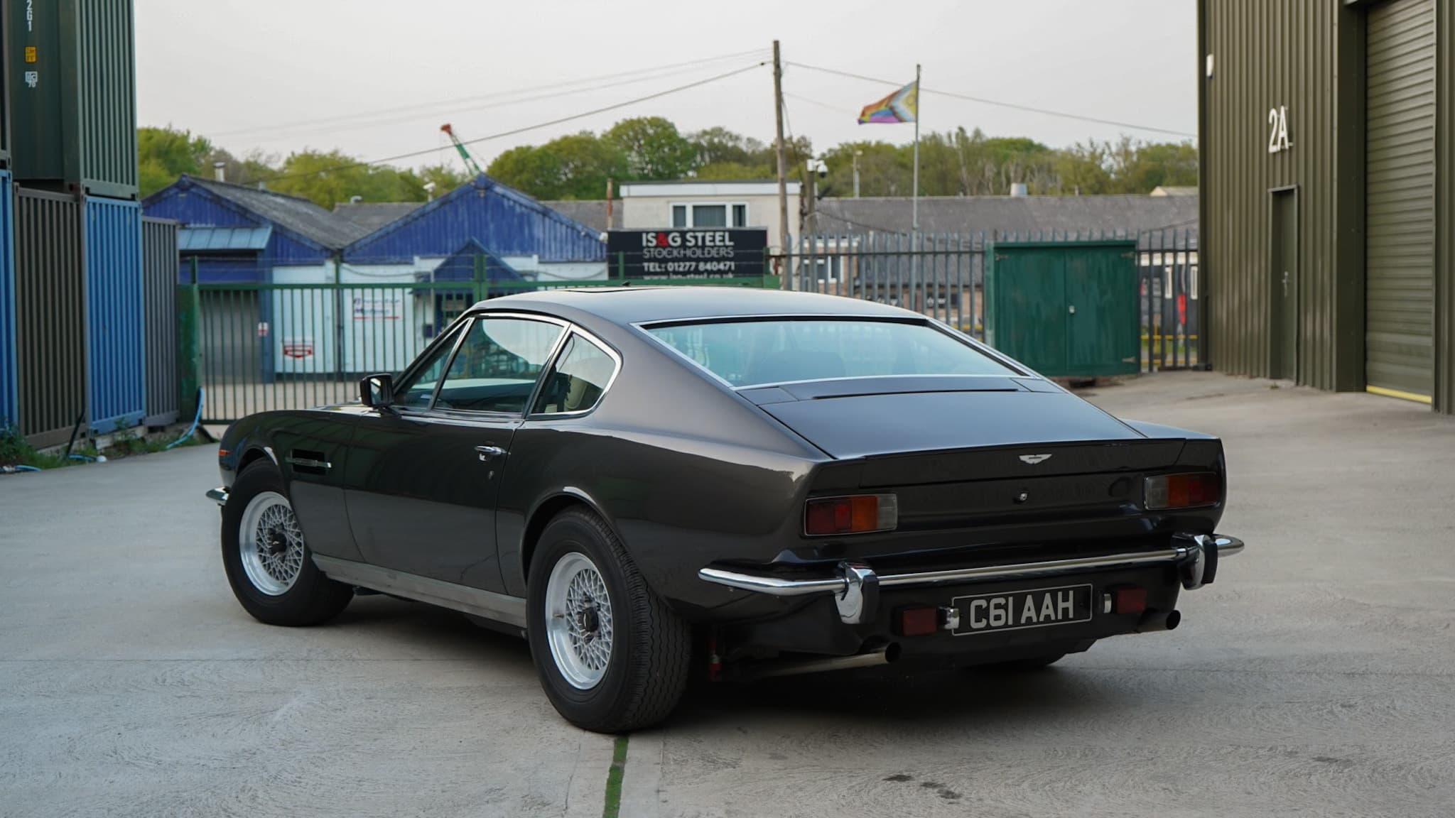 Dark brown 1985 Aston Martin V8 Saloon Series 4 “Oscar India” in a wide rear three-quarter view.