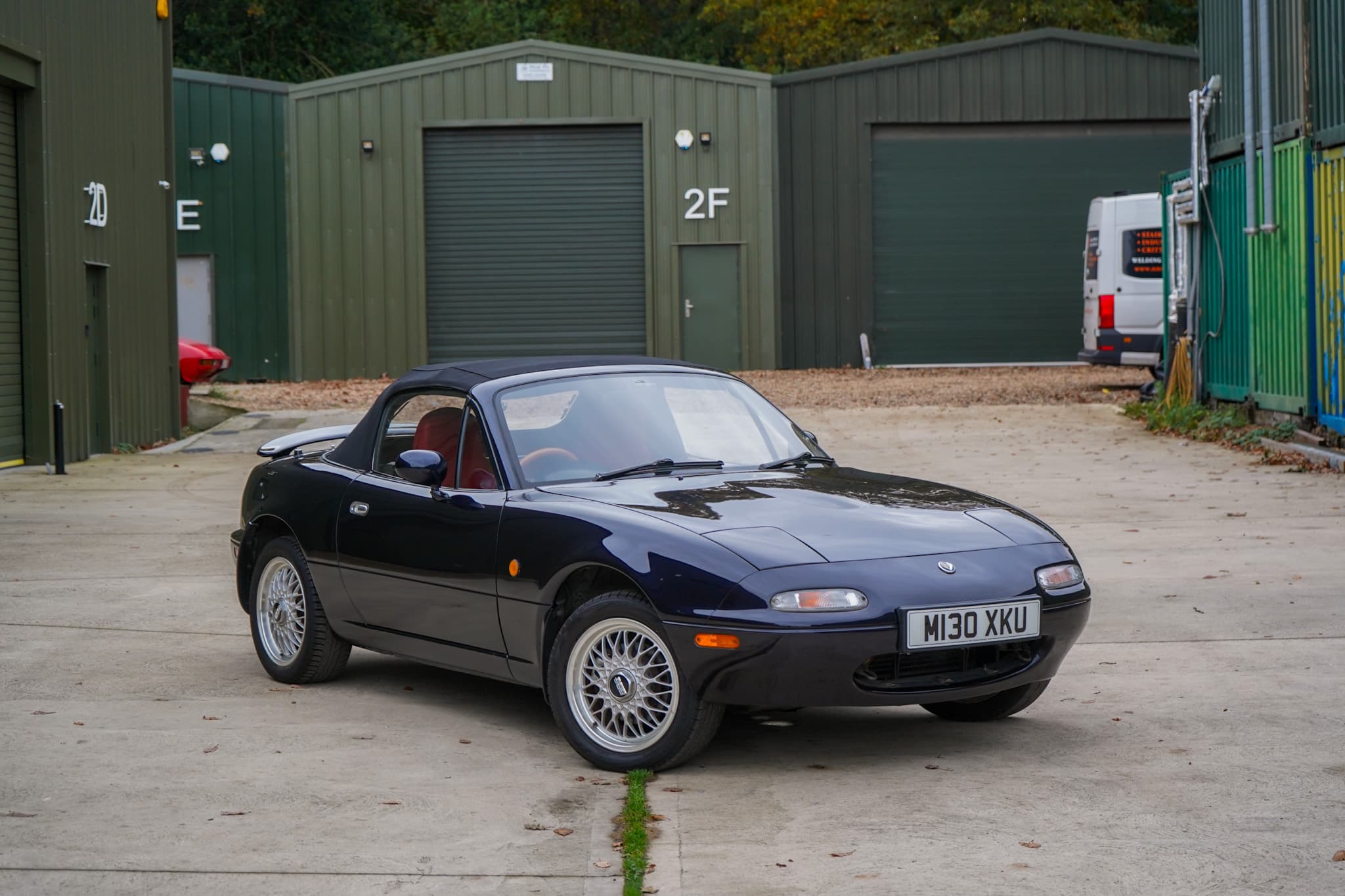 Dark blue 1995 Mazda MX-5 (NA) R-Limited in a wide front three-quarter view with the roof lowered.