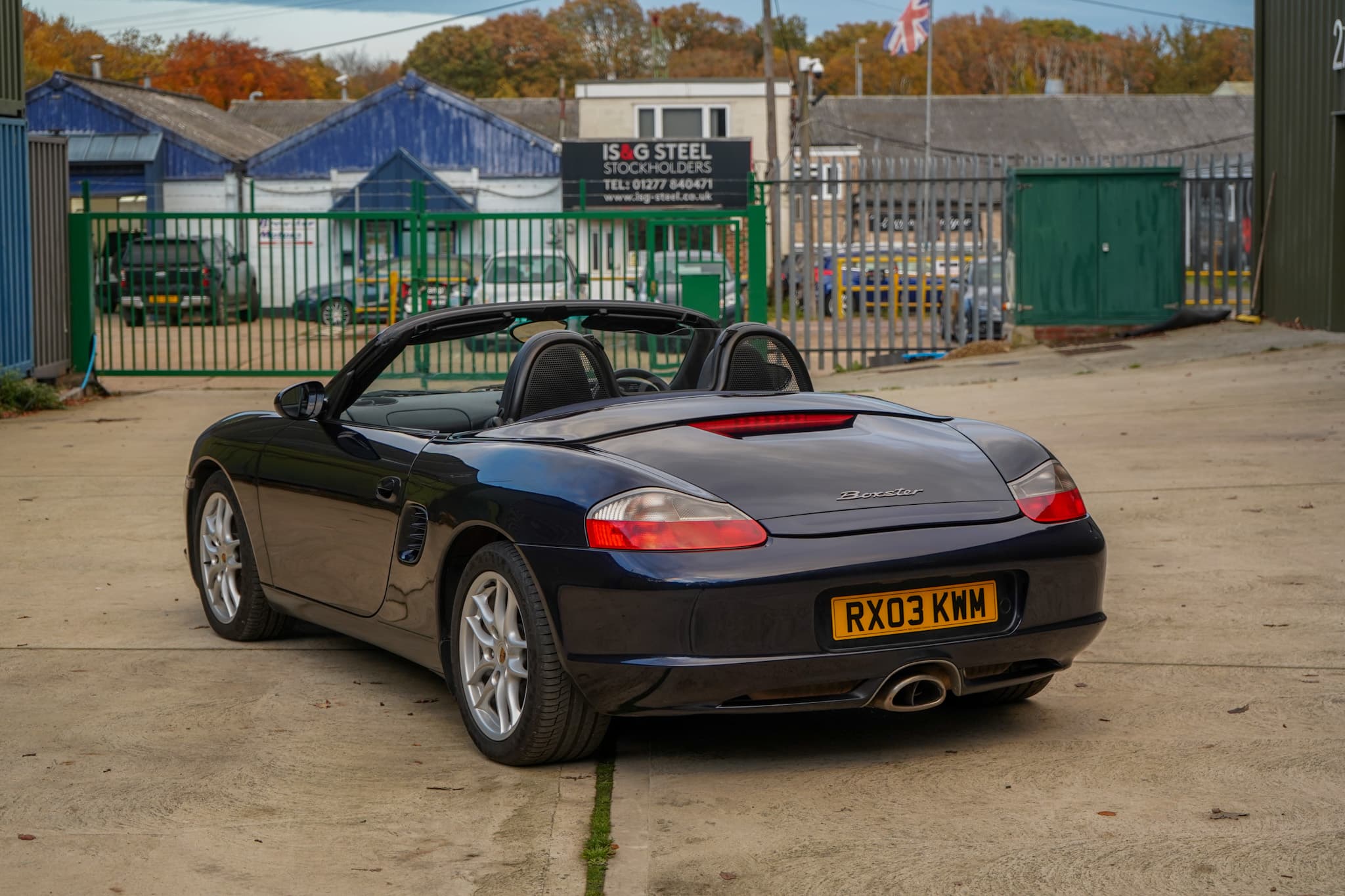 Dark blue 2003 Porsche Boxster (986) in a rear three-quarter view with the roof lowered.